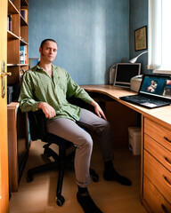 A man in a green plaid shirt works in a coworking space at a laptop