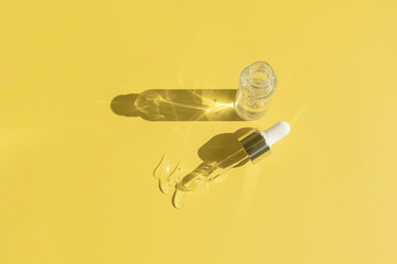 close up of pipette with pouring liquid serum and shadows