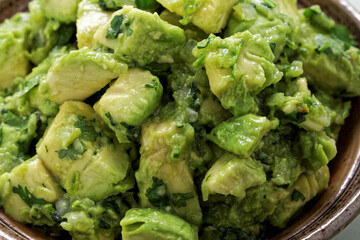 Close-up view of chunky guacamole in ceramic bowl. Mexican cuisine.