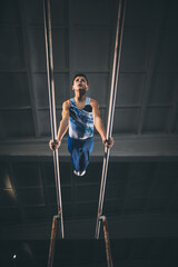 Little male gymnast training in gym, flexible and active. Caucasian fit little boy, athlete in sportswear practicing in exercises for strength, balance.