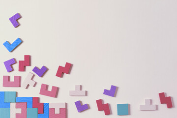 Different colorful shapes wooden puzzle blocks on pastel color background. Geometric shapes in...