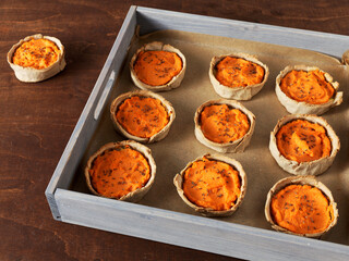Carrot pies top view in a tray. Pastry with carrot and potato filling with caraway seeds. Rye flour homemade pastry.