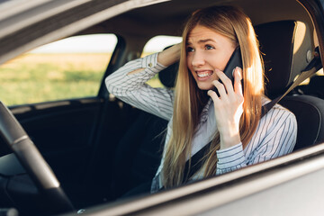young woman sitting in car talking on mobile phone while driving