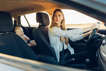 family on the road, happy young mother with her baby traveling in her car