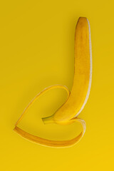 Partly peeled banana with heart shape made of fruit peel.