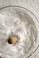 cream meringue, whipped egg whites, whipped cream in a cooking bowl with a whisk