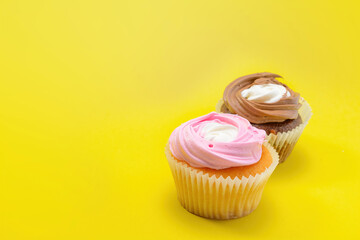 Chocolate and vanilla cupcakes with whipped raspberry and coffee cream on a yellow background. Selective focus.