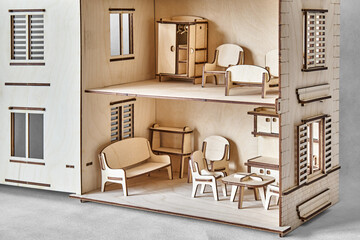 Cute doll house with toy furniture made of plywood details cut with laser machine tool stands with open wall on light grey closeup - obrazy, fototapety, plakaty