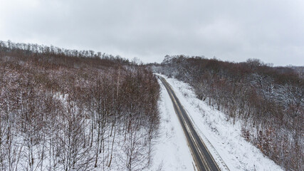 Aerial view on the road and forest at the winter time. Natural winter landscape from air. Forest under snow a the winter.