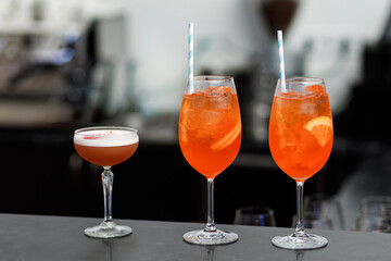 Five colored cocktails prepared by a bartender with pieces of orange and ice cubes