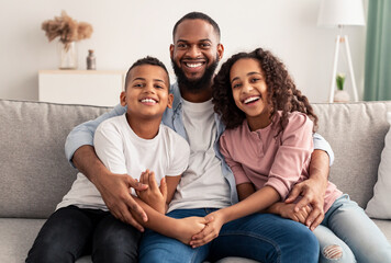 African american father hugging his children sitting on couch