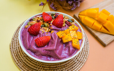 Close up Healthy food Acai breakfast superfoods smoothie bowl with chia seeds, bee pollen, fresh Strawberry, almond and granola for healthy vegan on color paper background
