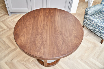 Fototapeta na wymiar Elegant round brown coffee table made of patterned veneer and solid walnut with acrylic part on floor in living room upper view