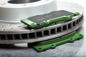 brake pads and perforated brake discs on a stone gray table