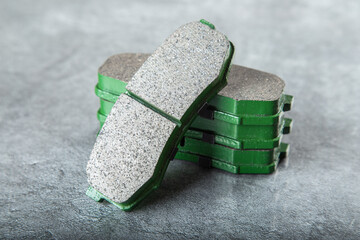 a set of new green brake pads on a gray table