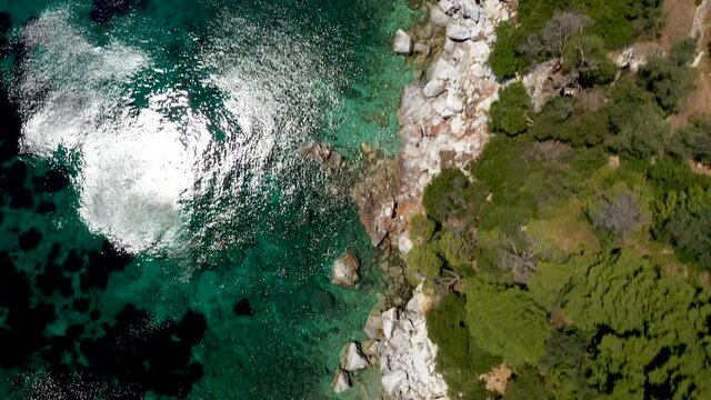 Aerial drone views over a rocky coastline, crystal clear Aegean sea waters, touristic beaches and lots of greenery in Skopelos island, Greece. A typical view of many similar Greek islands.