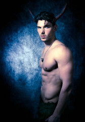Sexy shirtless male devil with horns and muscular body showing pecs and abs