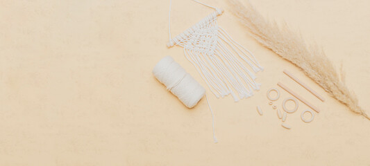 Fototapeta na wymiar Macrame accessories on beige background. Creative hobby concept. Top view. Vintage color filter