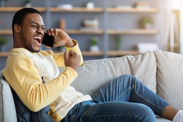 Emotional black man having conversation on phone, home interior