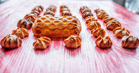 Homemade eclairs and jam puff on a wooden background.