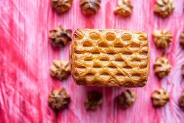 Homemade eclairs and jam puff on a wooden background.
