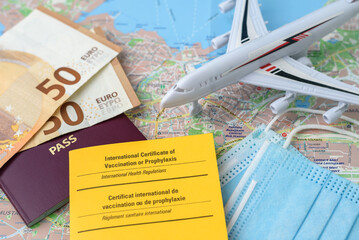 International certificate of vaccination with passport, money and face masks on travel map