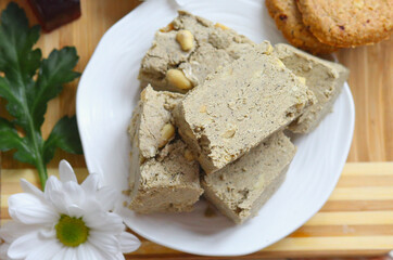 Flat lay a eastern sweets, halva on a white plate and a wooden background. Food. Delicious. Homemade sweets concept.