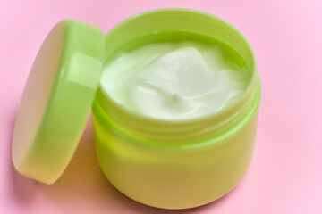 face cream in open jar on pink background