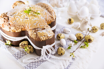 Traditional Italian desserts for Easter - Easter dove. Festive pastries with almonds and sugar icing on a light background and flowering branches, Easter decor and eggs. close-up