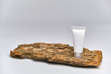 Facial moisturizer cream in white plastic tube on tree bark