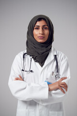 Studio Portrait Of Serious Young Doctor With Headscarf Wearing White Coat Against Plain Background