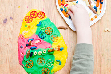 Easter concept. the child places colored noodles on an egg-shaped plasticine. children DIY toys for home ideas, child employment, fine motor skills, ergotherapy, sensory therapy