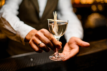 view of bartender man's hands presenting glass with drink