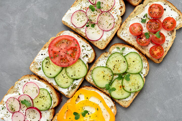 Healthy vegetarian sandwiches with vegetables - yellow pepper, tomato, cucumber and radish. Cream cheese and microgreens