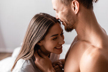 Muscular man smiling while touching pretty girlfriend at home