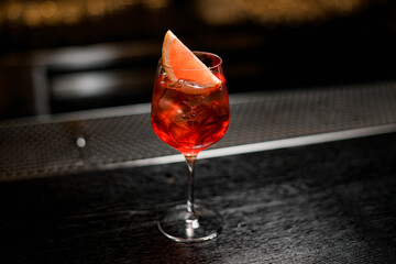 view of beautiful wine glass with bright cold iced drink decorated with citrus slice