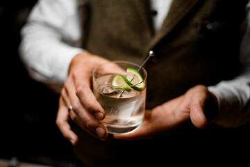 Great close-up view of glass with freshness drink in hands of male bartender