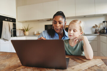 Mom and little girl watching something on a laptop