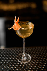 close-up of wine glass with refreshing drink decorated with citrus zest on bar