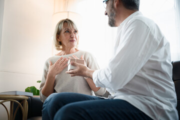 Fototapeta premium Elderly old man give a present to old woman in the warm light atmosphere, Romantic elderly husband surprise his wife with a present for anniversary. Happy senior people lifestyle at home.