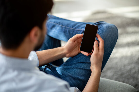 Over The Shoulder View Of Unrecognizable Man Using Cellphone With Black Empty Screen For Mockup