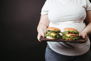 Obese woman with two tasty fattening hamburgers