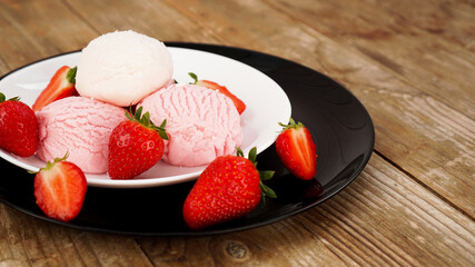 Delicious strawberry ice cream with fresh strawberrieson a white and black plate