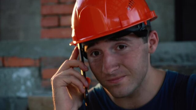 tired and dirty worker in hard hat speaks on the phone