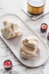 Homemade sweet meringue cookies and cup of coffee on white marble table. Delicious and light dessert. Selective focus