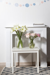 Bouquet of white lilies in a tall glass vase on a beige table against a gray wall. Copy space. Fresh bud