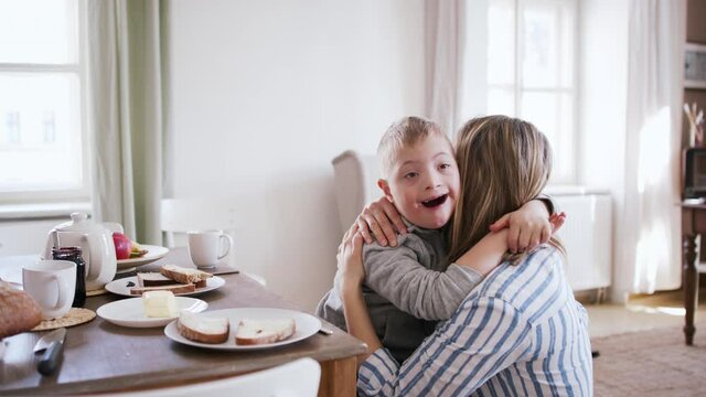 Single mother hugging her down syndrome son at home.