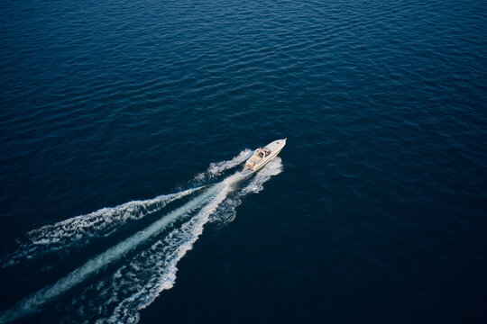 Yacht in the rays of the sun on blue water.  Aerial view luxury motor boat. Drone view of a boat sailing. Large speed boat moving at high speed side view. Travel - image.