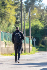 young man with a backpack and mohican walking across the street view from the back
