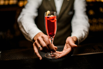 Wine glass with bright alcoholic cocktail in hands of male bartender